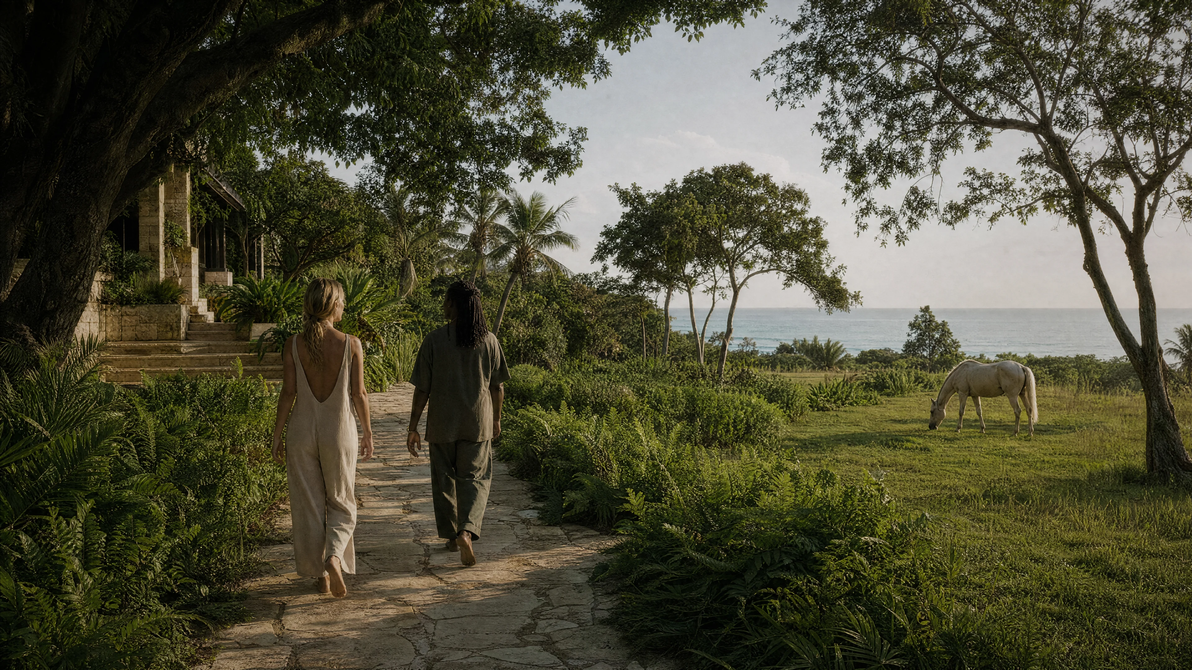 Two guests walking a garden path toward the sea